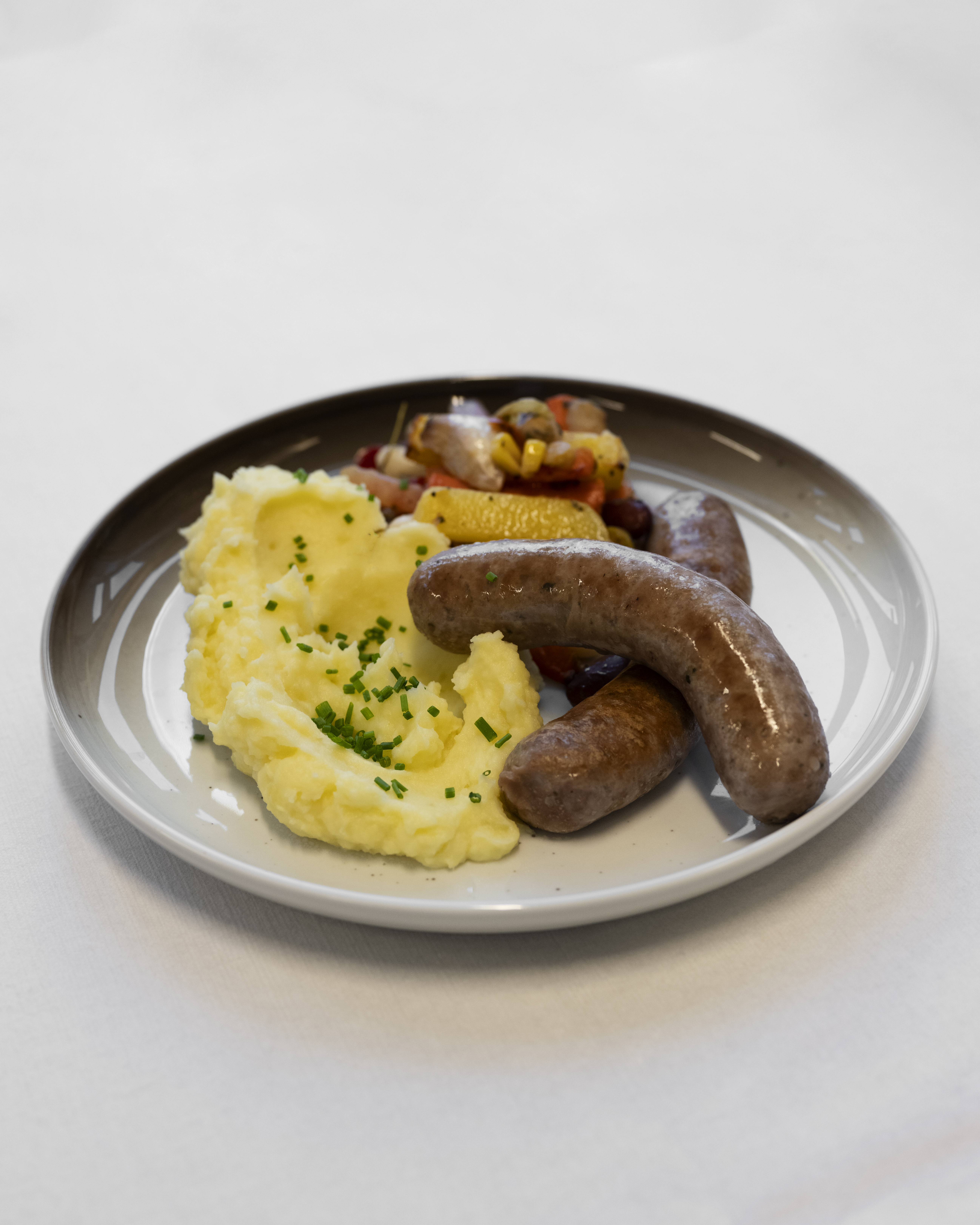 Lammepølser m mos og grønnsaker på hvit bakgrunn